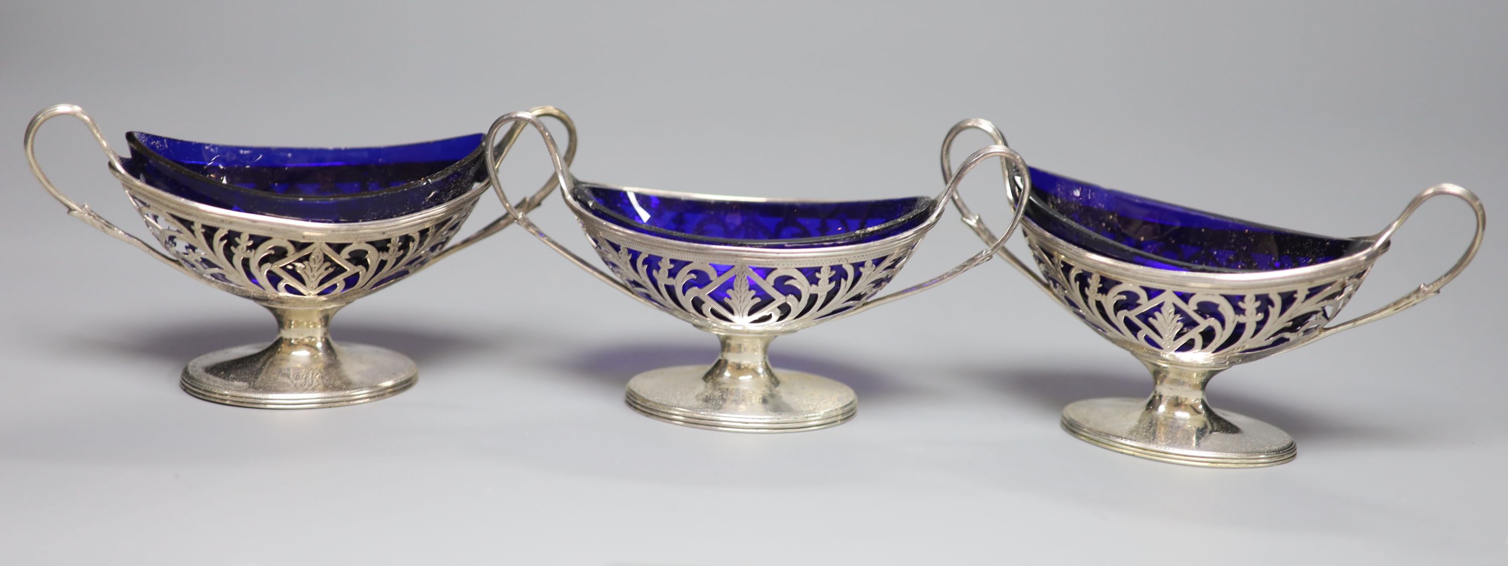 A matched set of three George III pierced silver salts with blue glass liners, London, 1788 and 1792